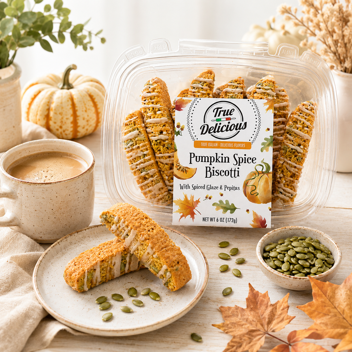 A package of True Delicious Pumpkin Spice Biscotti with Glaze & Pepitas is served alongside a cup of coffee, a small bowl of pepitas, autumn leaves, and a decorative pumpkin atop a wooden table, creating a cozy fall ambiance. Made with natural ingredients, these biscotti capture the essence of the season.