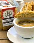 Jar of True Delicious Whole Almond Biscotti with a cup of coffee on a wooden surface