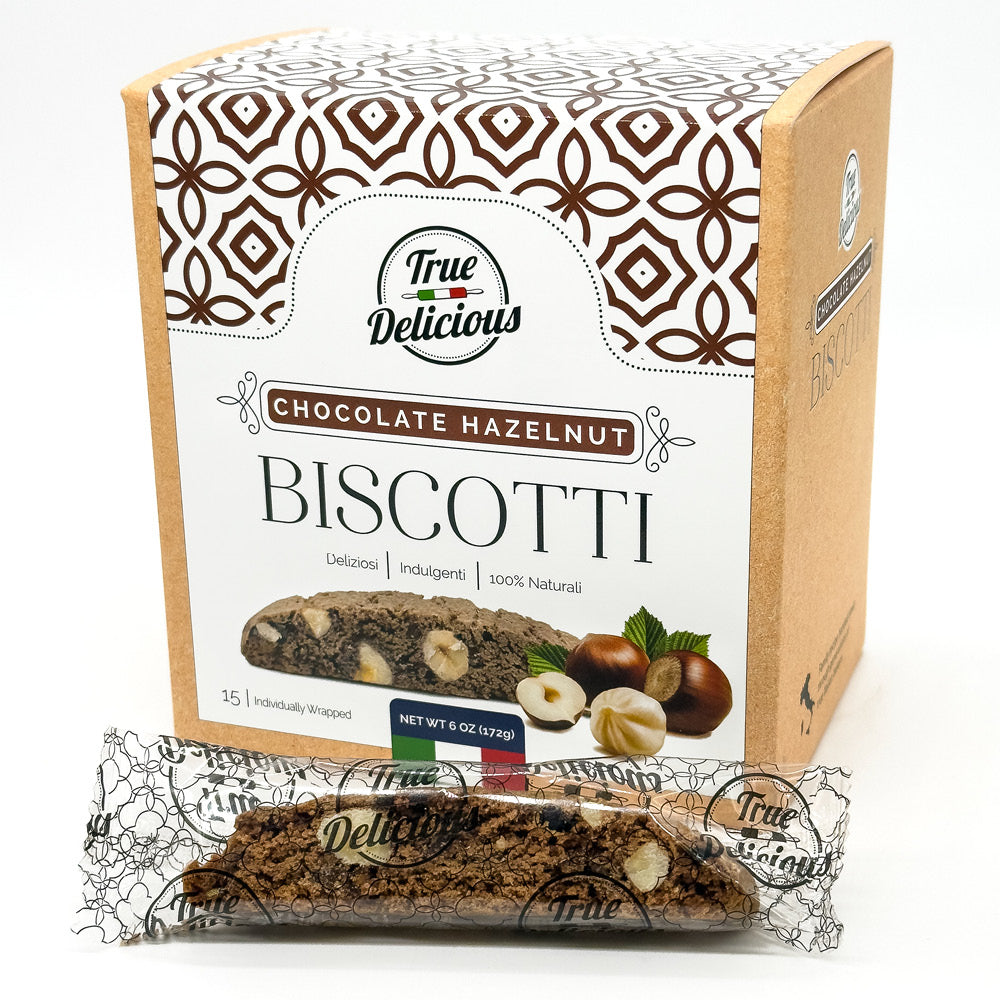 A box of True Delicious Elegant Box Chocolate Hazelnut Biscotti Individually Wrapped is shown with geometric packaging, and a wrapped biscotti featuring visible chocolate and hazelnut pieces is displayed in front.