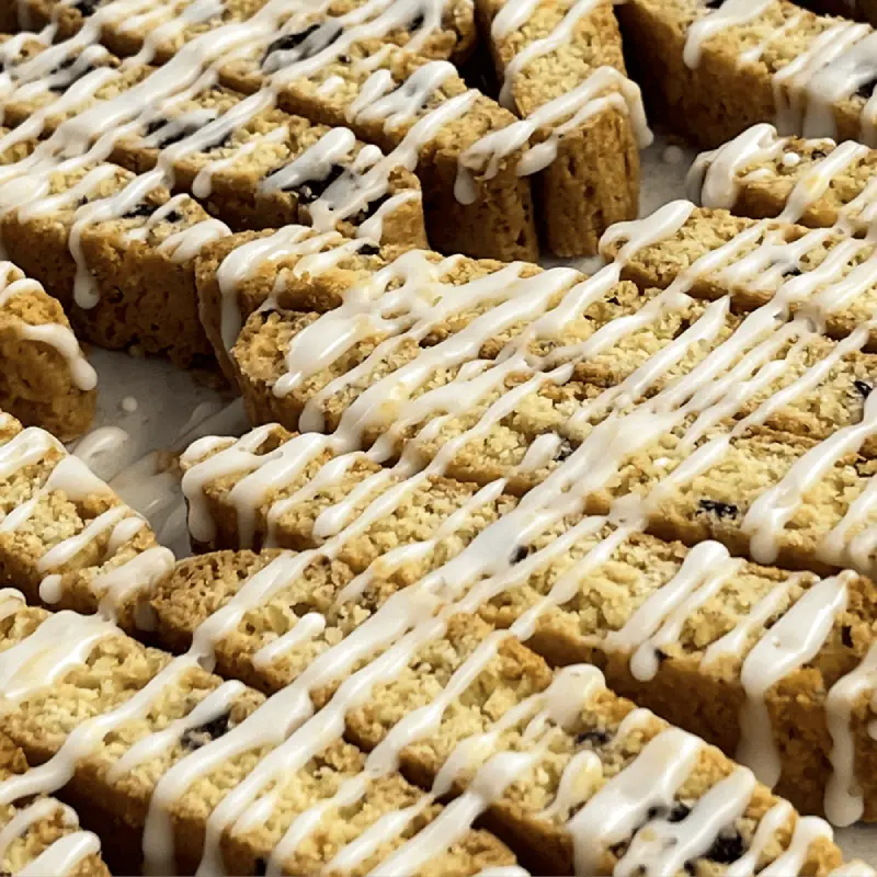 Biscotti cookies with white icing drizzled over them on a white surface