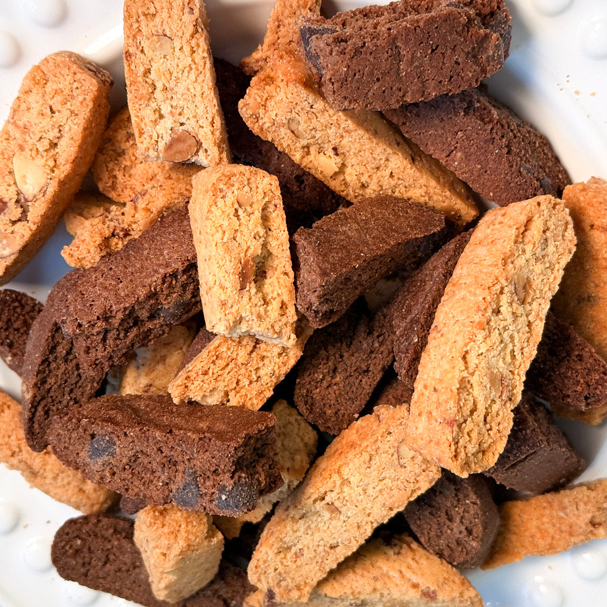 A close-up of True Delicious Sugar Free Biscotti Bits - Almond &amp; Chocolate 2lbs, shows their crunchy texture and assorted keto-friendly flavors, with light and dark pieces made from almond flour.